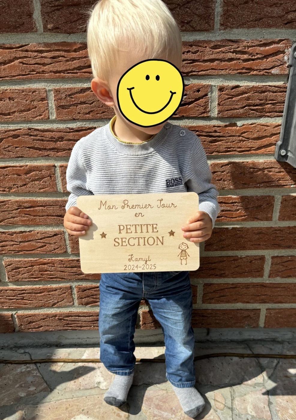 Enfant tenant sa plaque premier jour d'école