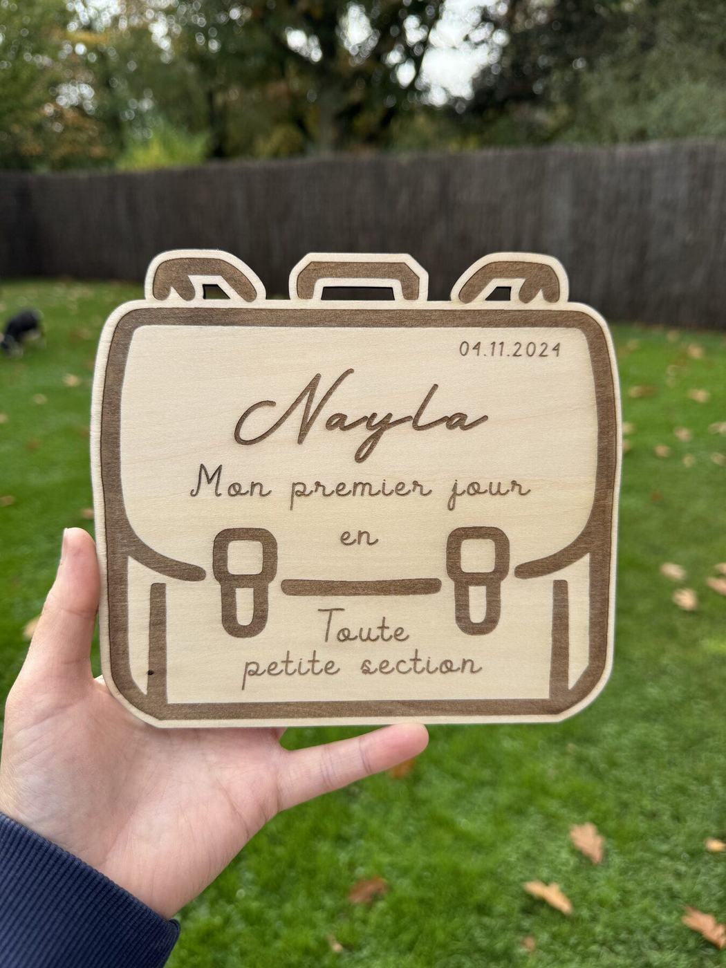 Plaque premier jour en forme de cartable, prénom Nayla, toute petite section